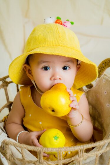 Image of a cute baby holding fruit in his hand